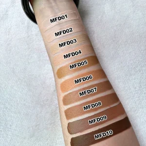 Beige foundation makeup displayed in a transparent skull bottle with black cap Liquid foundation in a clear skull-shaped cosmetic bottle with beige makeup swatches